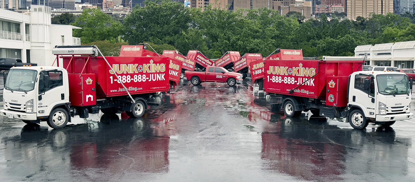 A parking lot with several branded Junk King dump trucks.