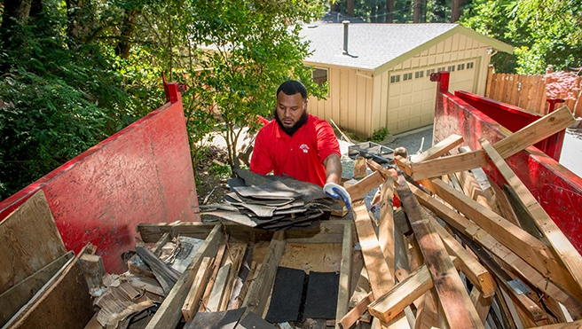 A Junk King professional loading boards into a branded dump truck.