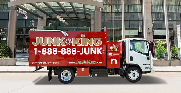 A branded Junk King dump truck parked in front of a hotel.
