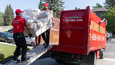 Two Junk King workers loading a truck.