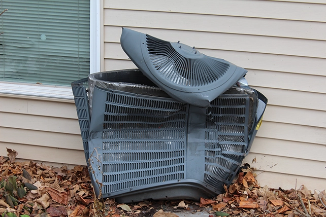 Dented air conditioning unit outside of a home.