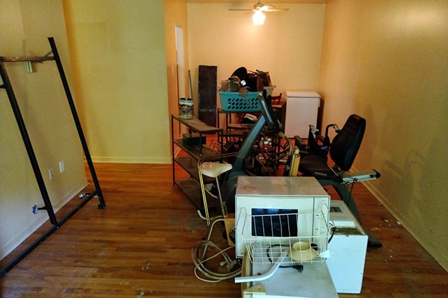 An apartment living room with a pile of junk to clean out.