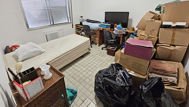 A bedroom with an old mattress and a lot of boxes stacked against the wall.
