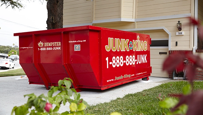A red dumpster outside of a garage.