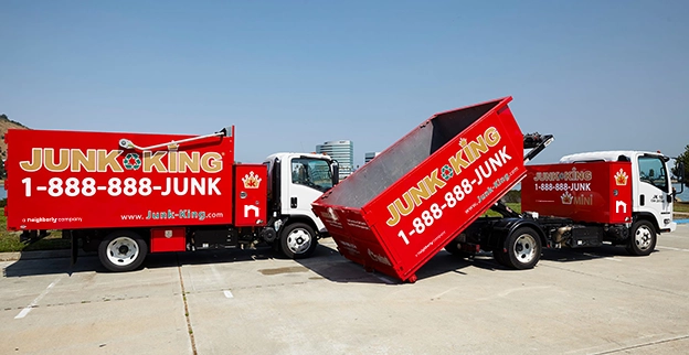 Two red Junk King dump trucks.
