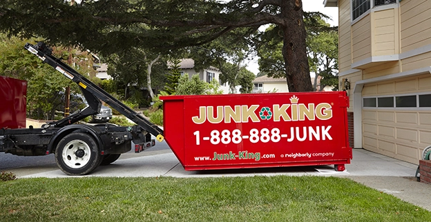 A red dumpster being delivered to a home.