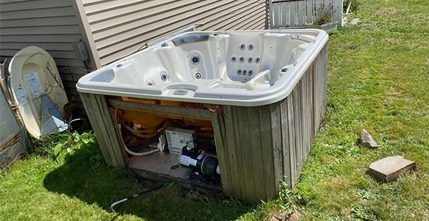 A non-working hot tub sitting in a yard.