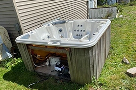 Broken hot tub sitting outside of a home.