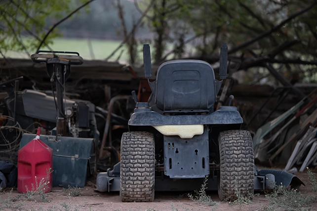 An old riding lawnmower with a gas can next to it.
