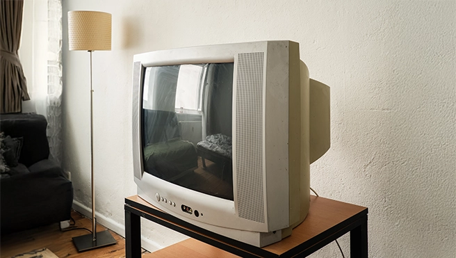 An old television on a stand in a living room next to a lamp.