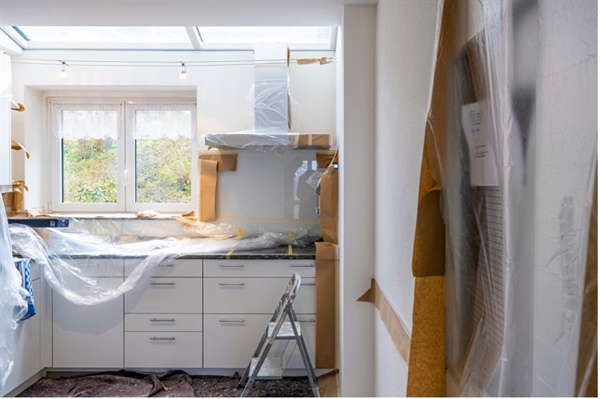 A kitchen featuring a skylight and cabinets wrapped in plastic, indicating ongoing renovations.