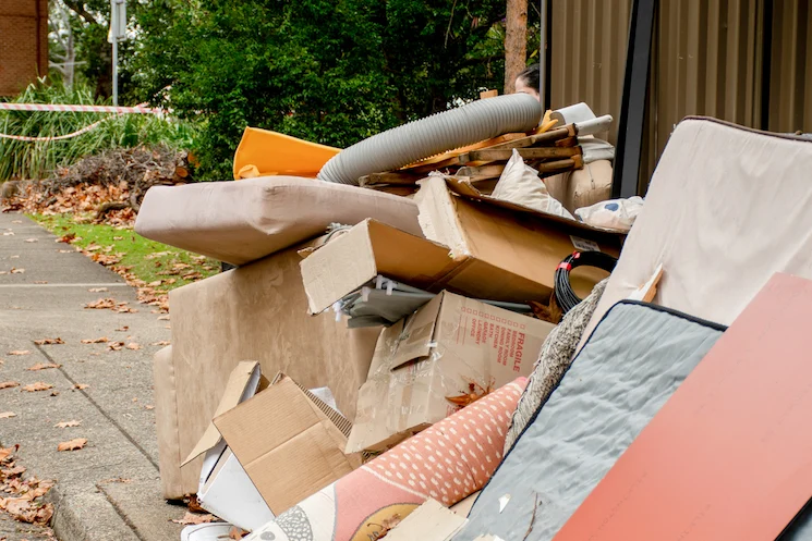 A pile of discarded furniture, cardboard boxes, and debris.